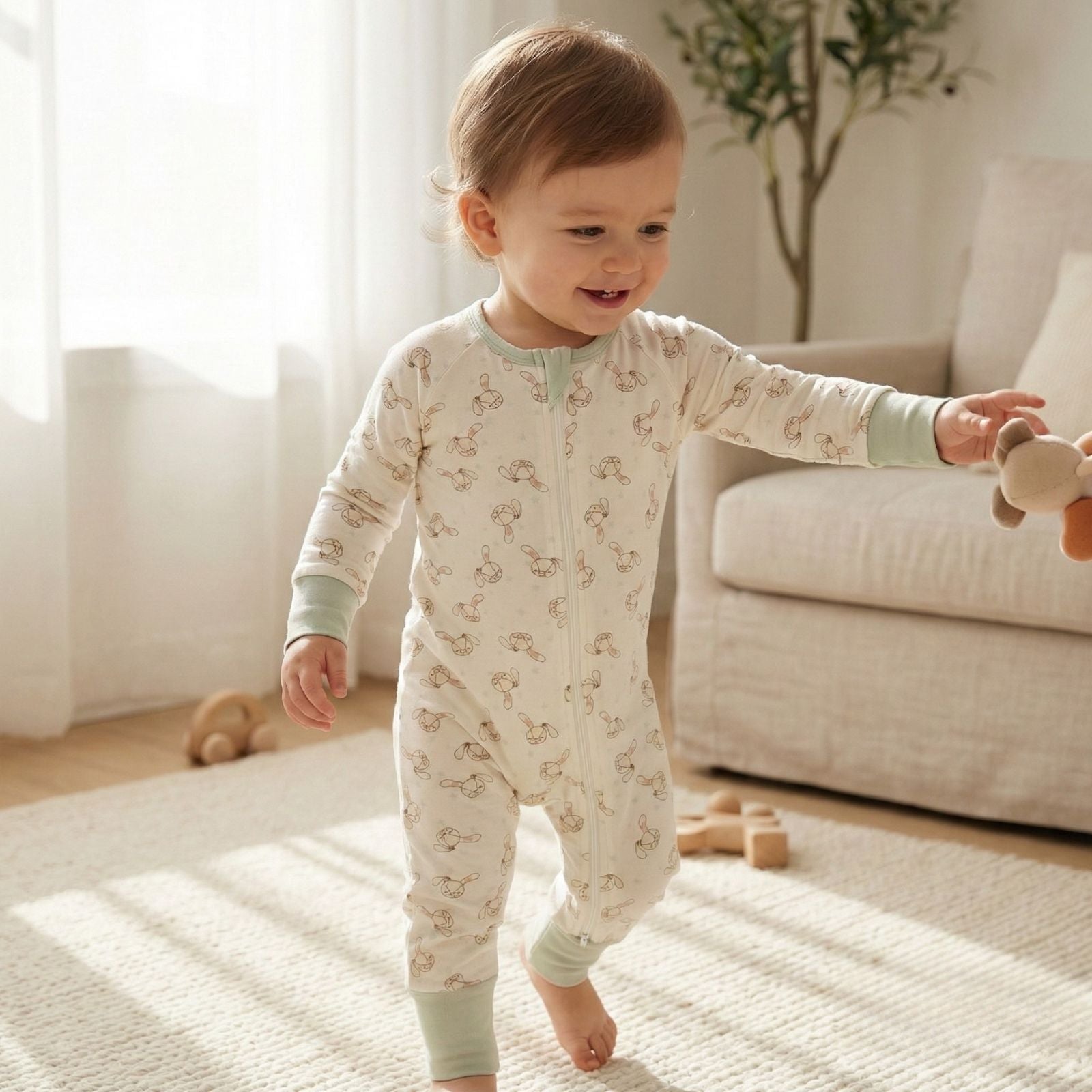 Toddler taking first steps on a soft nursery rug while wearing Zelkii® bamboo pajamas in natural daylight.