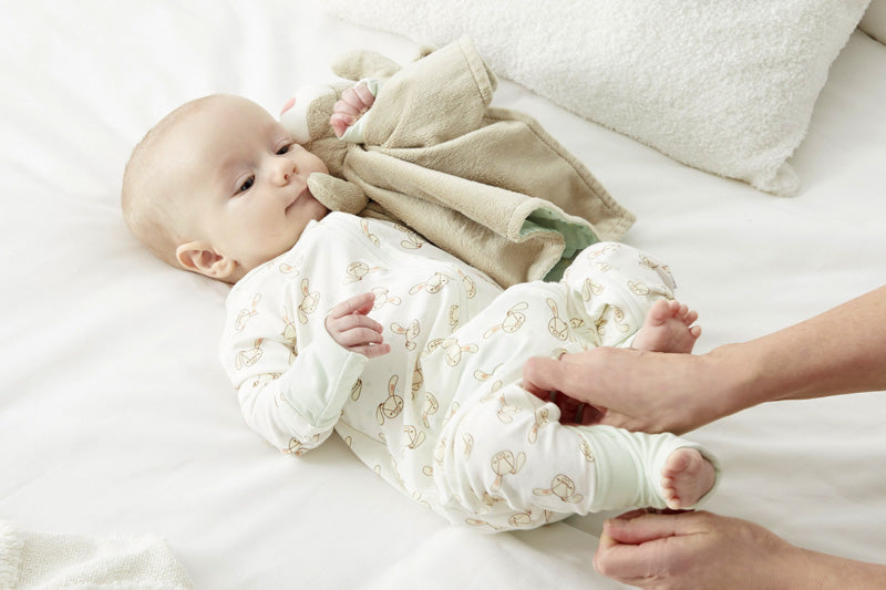 A baby in Zelkii's bunny-print pyjamas, holding the 'awake' bunny LuviDuvi lovey.