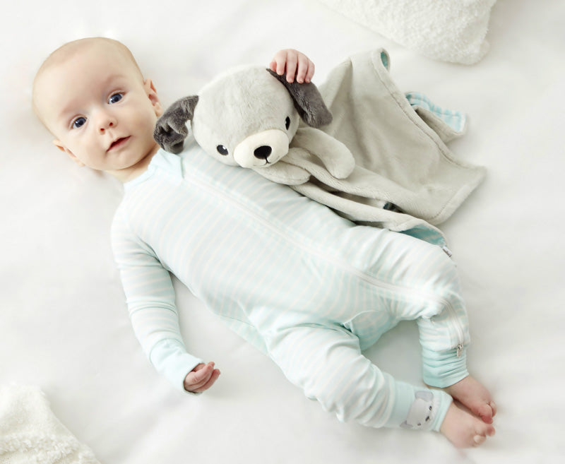 A baby in Zelkii's striped pyjamas (with a puppy on the cuff) lies next to the 'asleep' Zelkii puppy LuviDuvi lovey.