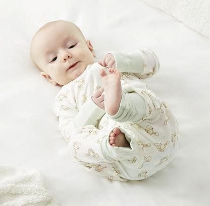 A baby in Zelkii's bunny-print pyjamas, lying on its back and looking up.